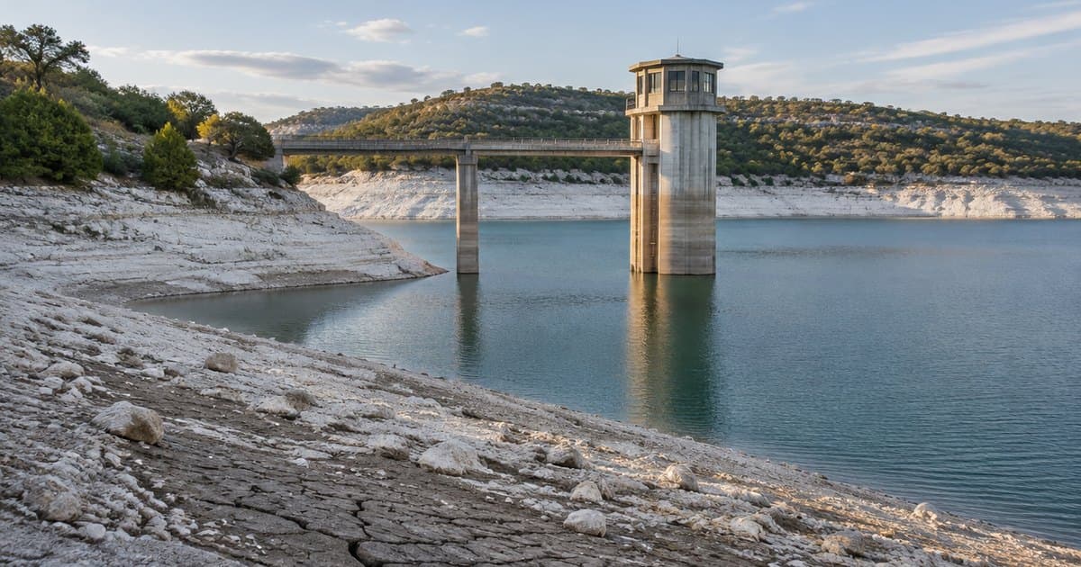 A concrete water intake tower stands in a Hill Country lake below a wide band of exposed white limestone shoreline and cracked mud, with cedar-covered hills behind. AI illustration.